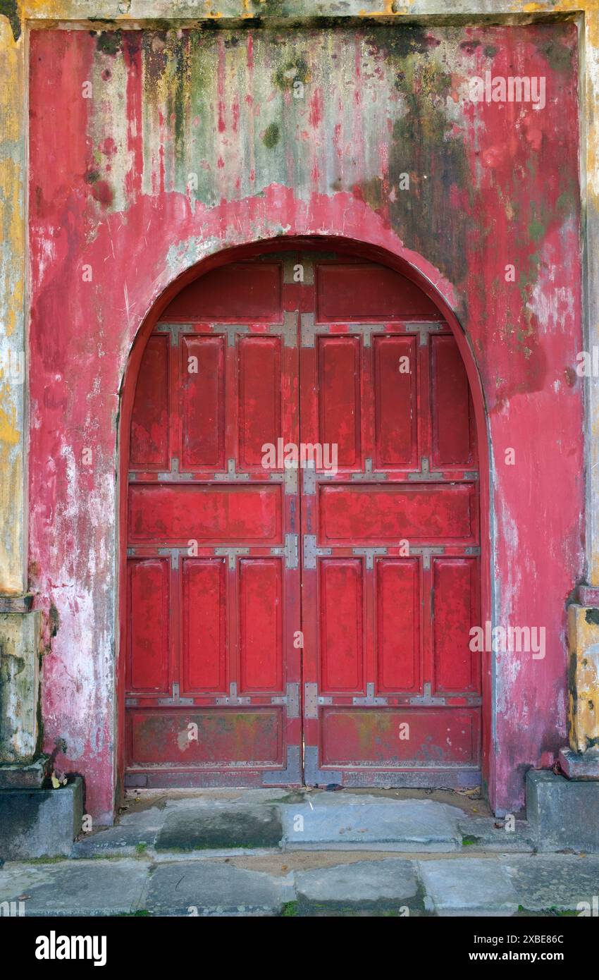 Vietnam: Eine Tür in der Nähe des Thế Miếu (der Mieu) Ahnentempels, der Kaiserstadt, der Zitadelle, Hue. Der Thế Miếu ist ein Ahnentempel, der 1822–23 auf Befehl von Kaiser Minh Mạng errichtet wurde. Er ehrt die Kaiser der Nguyễn-Dynastie. Kaiser Gia Long ordnete 1805 den Bau der Zitadelle von Hue an. Der weitläufige Komplex wurde nach den Vorstellungen des Fengshui oder der chinesischen Geomanz errichtet, aber nach den militärischen Prinzipien des bekannten französischen Militärarchitekten Sebastien de Vauban aus dem 18. Jahrhundert. Stockfoto