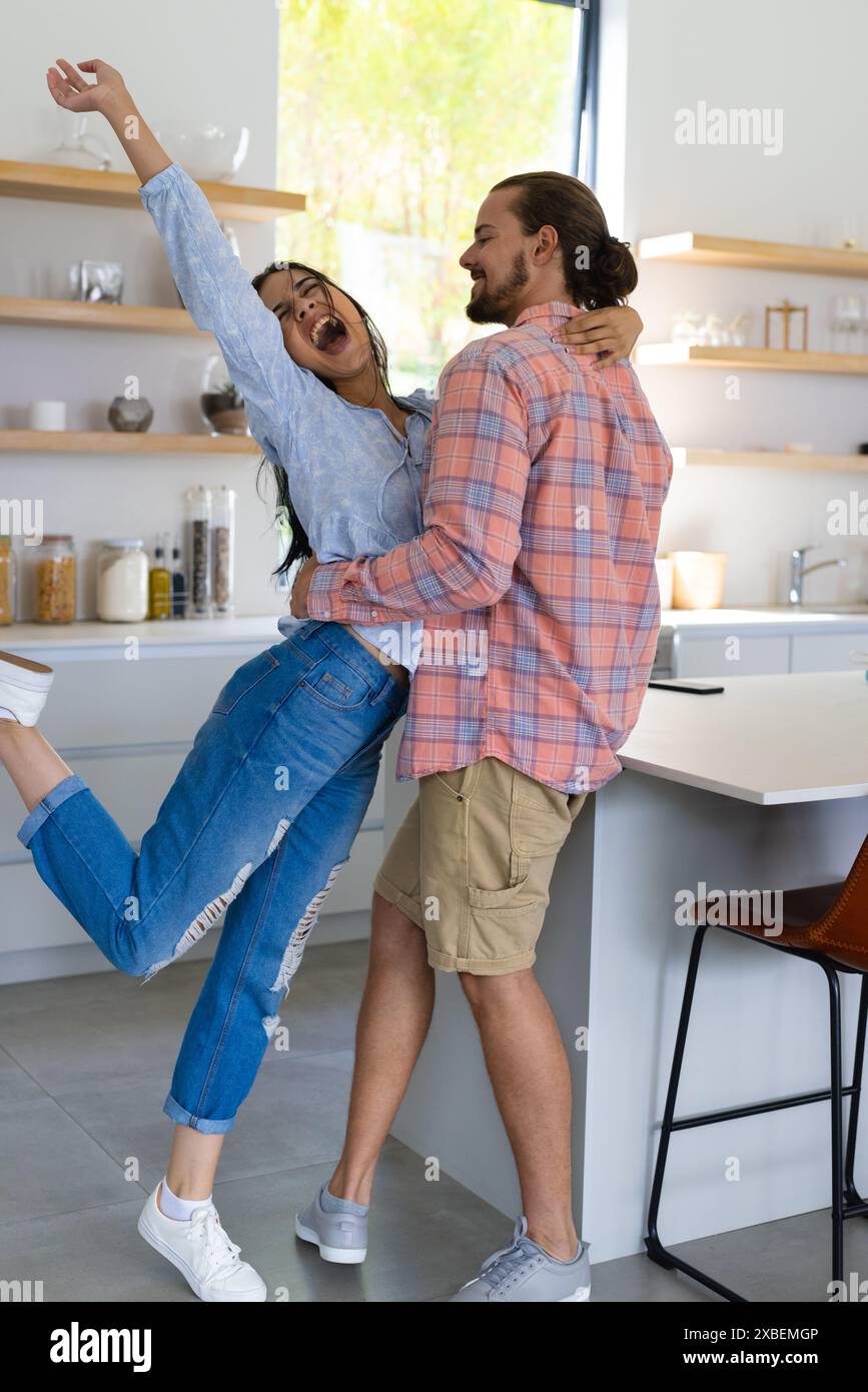 Junge, vielfältige Paare umarmen und lächeln in einer modernen Küche Stockfoto