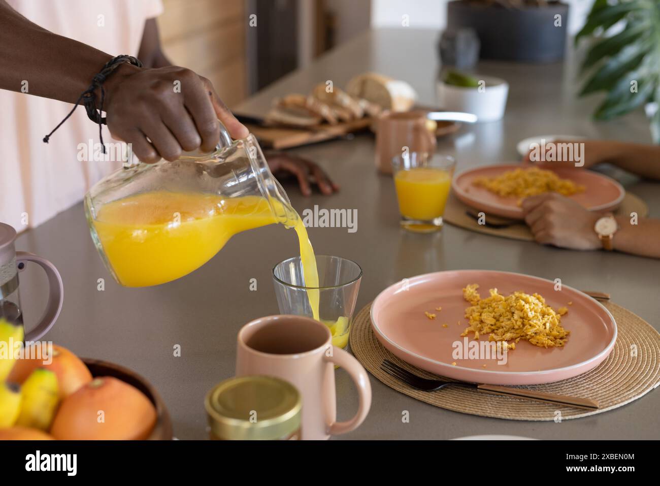 Ein afroamerikaner, der Orangensaft ins Glas gießt Stockfoto