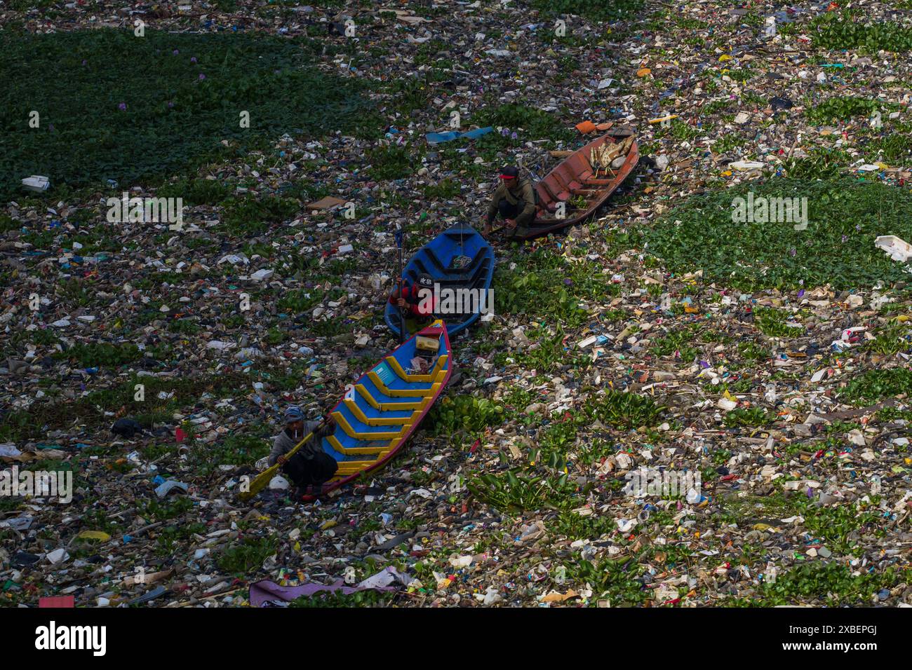 Bandung, West-Java, Indonesien. Juni 2024. Offiziere, die ein Holzboot benutzen, reinigen Plastikmüll, der sich im Citarum River in Batujajar, West Bandung Regency angesiedelt hat. Auf der Grundlage von Daten des Umweltministeriums der Regency West Bandung ist der Abfall, der seit Freitag (6.7.2024) im Fluss Citarum im Gebiet Batujajar angesiedelt ist, 3 km lang und 60 m breit und hat ein geschätztes Volumen von mehr als 100 Tonnen Kunststoffabfall. (Kreditbild: © Algi Febri Sugita/ZUMA Press Wire) NUR REDAKTIONELLE VERWENDUNG! Nicht für kommerzielle ZWECKE! Stockfoto