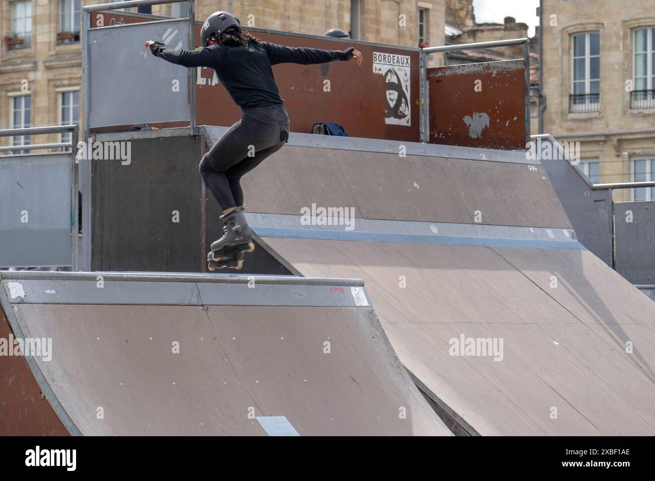 Rollerblader mit Sprüngen im örtlichen Skatepark, junge Leute auf Rollschuhen führen Tricks auf der Rampe aus. Extremsport Stockfoto
