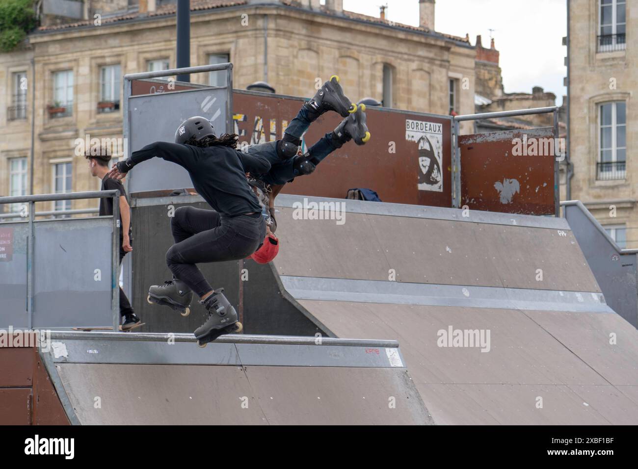 Rollerblader mit Sprüngen im örtlichen Skatepark, junge Leute auf Rollschuhen führen Tricks auf der Rampe aus. Extremsport Stockfoto