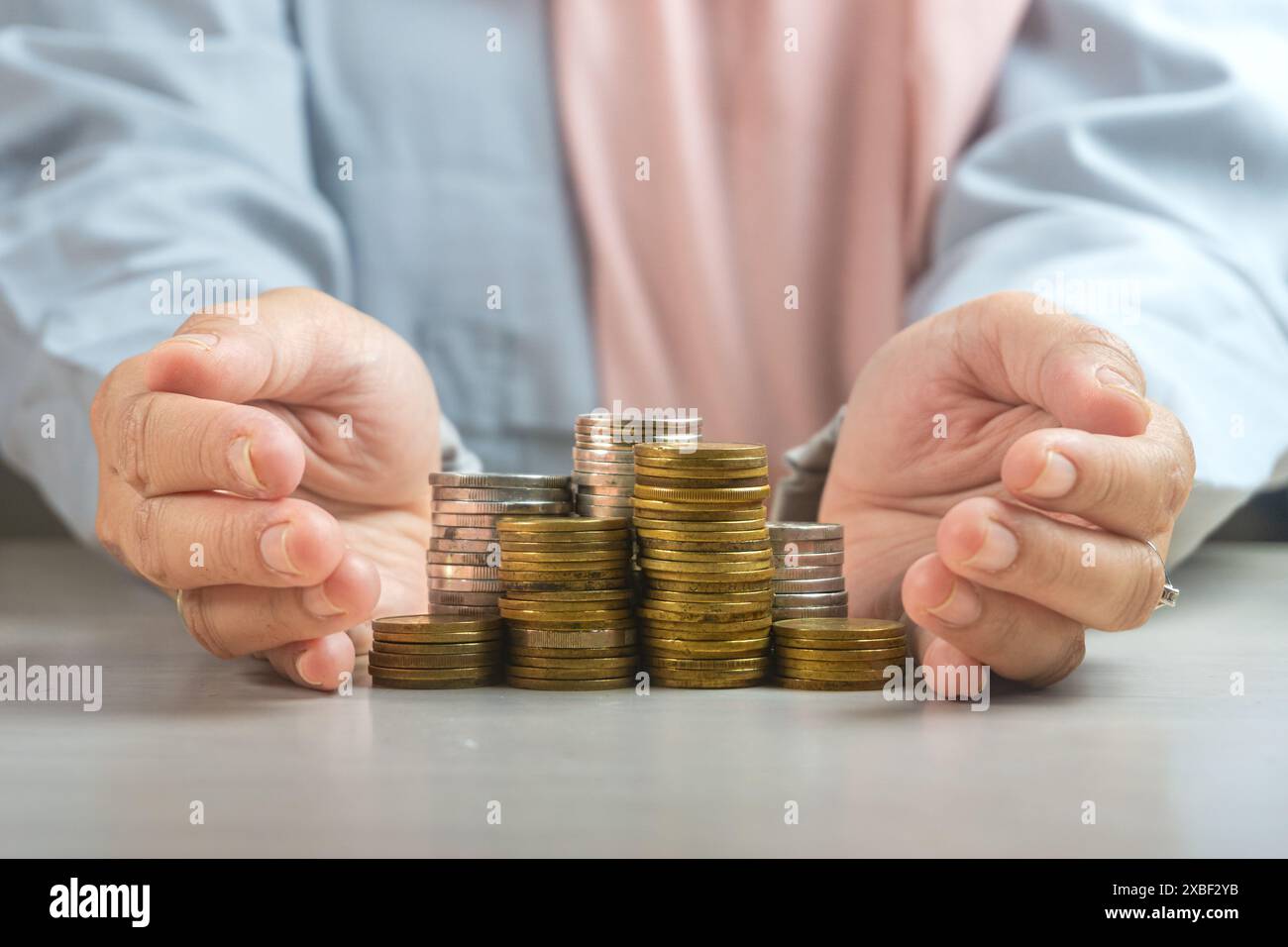 muslimische Geschäftsfrau Hand schützen einen Haufen von Münzen Geldsymbol für die Scharia Finanzbankinvestitionsdividende aus dem Konzept des Unternehmenswachstums. Stockfoto