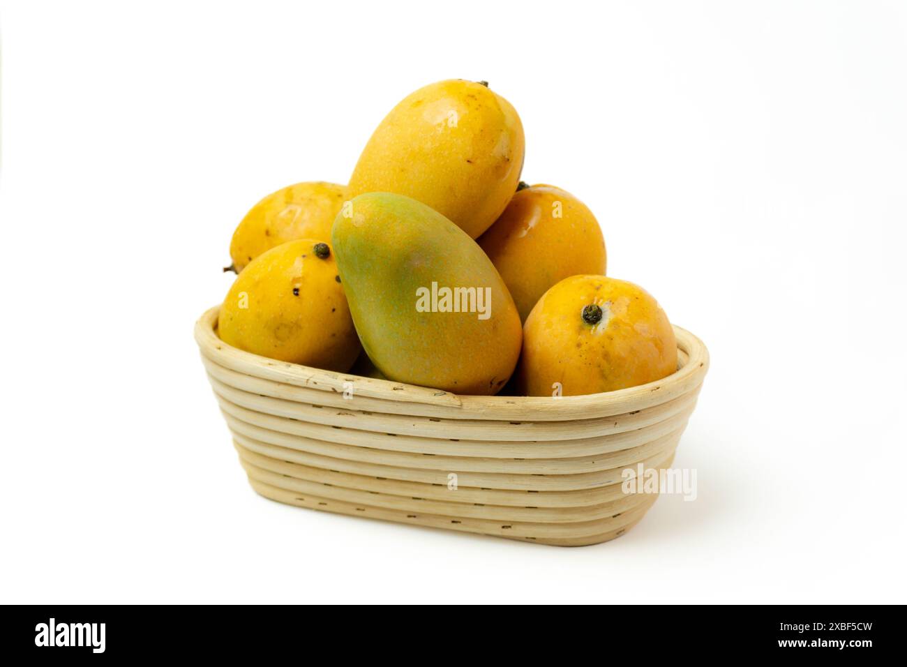 Stapel reifer Mango auf einem Korb aus Rattan, isoliert auf weißem Hintergrund, Draufsicht Stockfoto