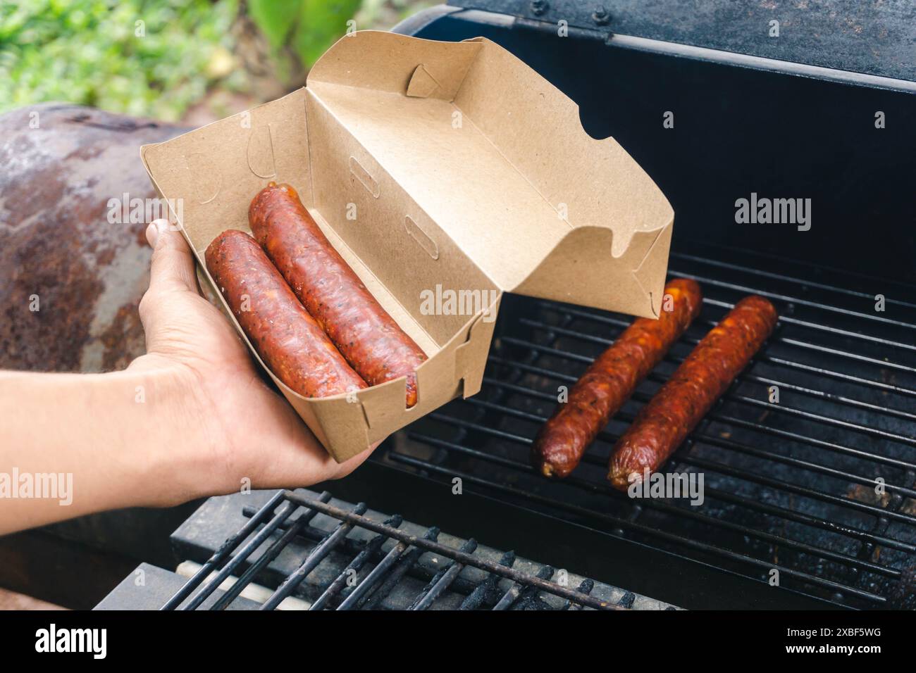 Geräucherte Würstchen, die bereits gekocht sind, werden vom Koch verpackt, Konzept des kleinen Unternehmens Stockfoto