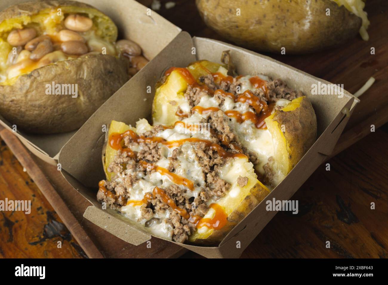 Hausgemachte beladene gebackene Kartoffeln mit Cheddar, Hackfleisch und süß-saurer Sauce Stockfoto