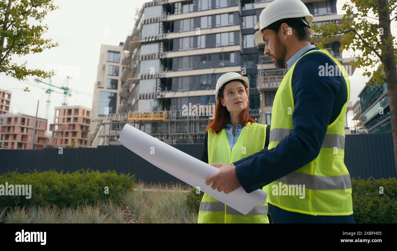 Zwei Architekten Stadtbauarbeiter kaukasische Kollegen mit Sicherheitshut und reflektierender Weste sprechen über Stadtbauingenieure Stockfoto