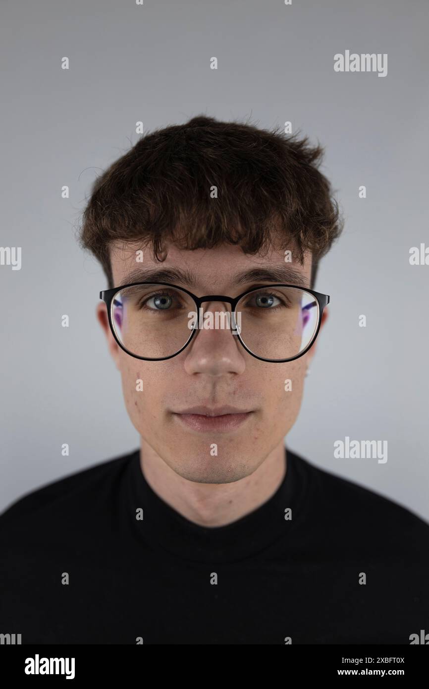 Weißes Hintergrundporträt im Atelier eines jungen Mannes mit Sehbrille Stockfoto