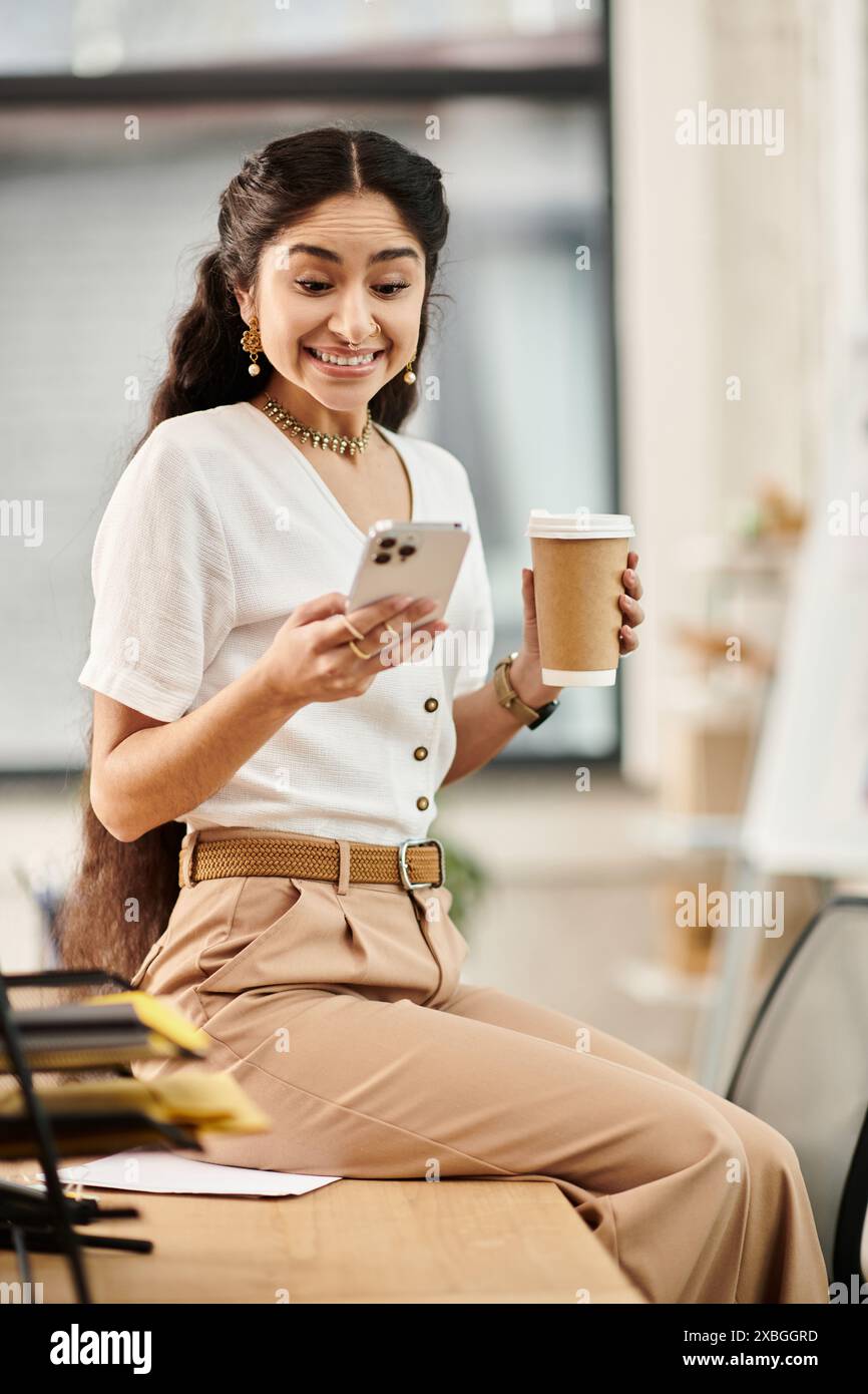 indische Frau mit Kaffee und Telefon an der Rezeption. Stockfoto