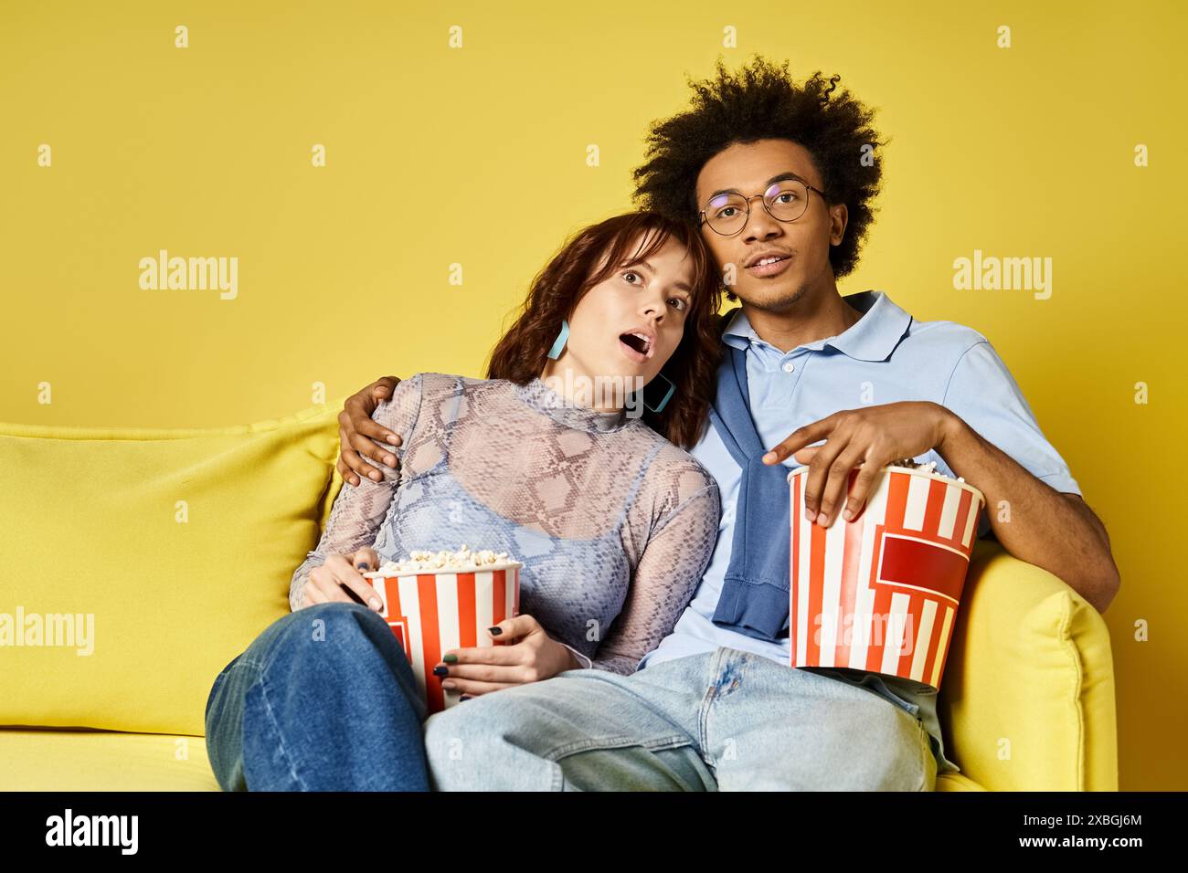Ein Mann und eine Frau entspannen sich auf einer Couch und genießen Popcorn zusammen. Stockfoto