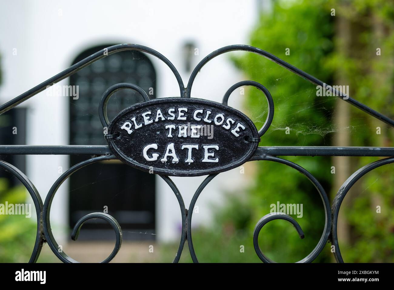 England - ein großes altes Landhaus mit schwarzem Eisentor mit dem Text 'Bitte schließen Sie das Tor' Stockfoto