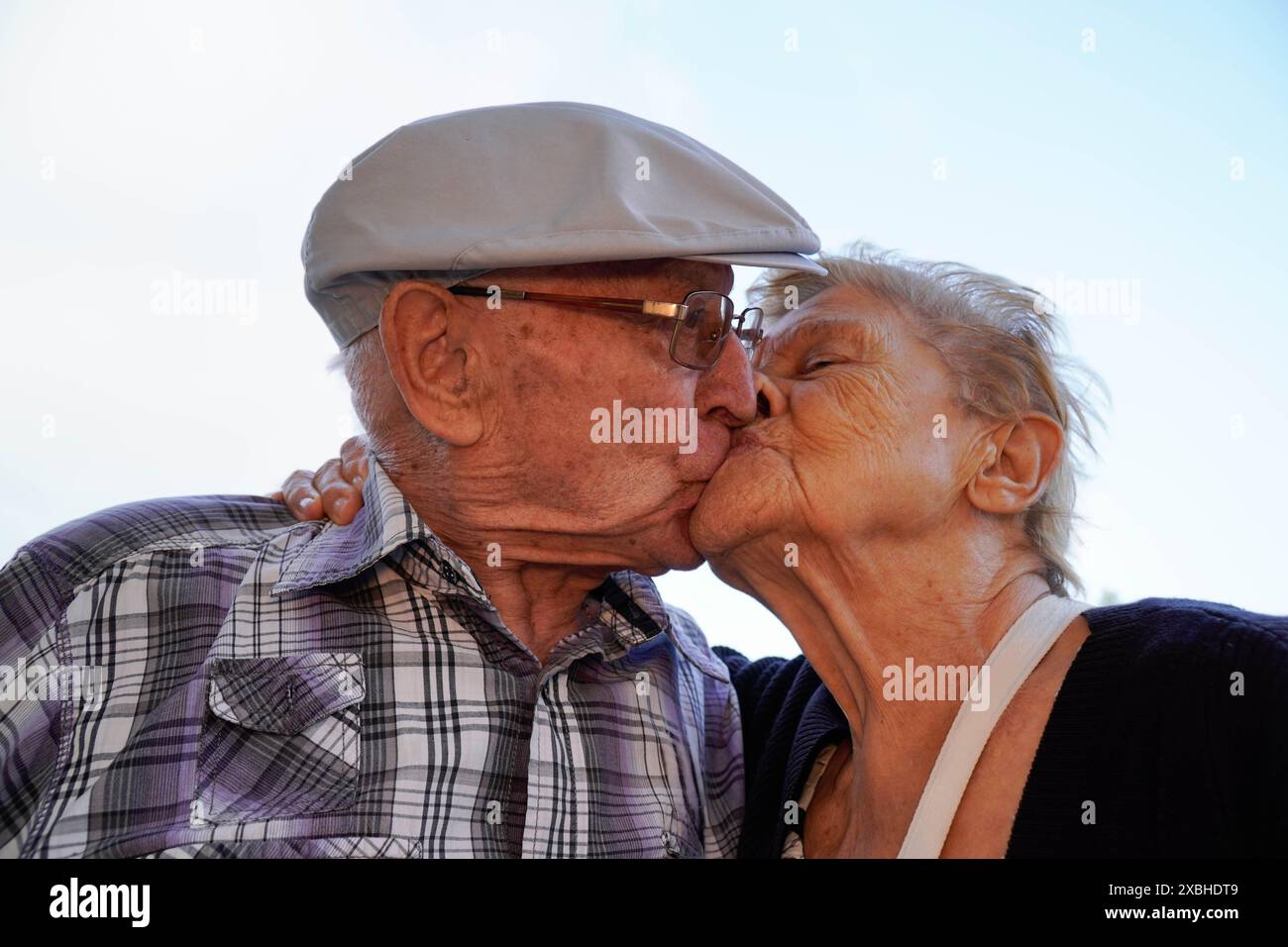 Ein älteres Paar küsst sich mit dem Himmel im Hintergrund. Liebe in der Familie. Stockfoto