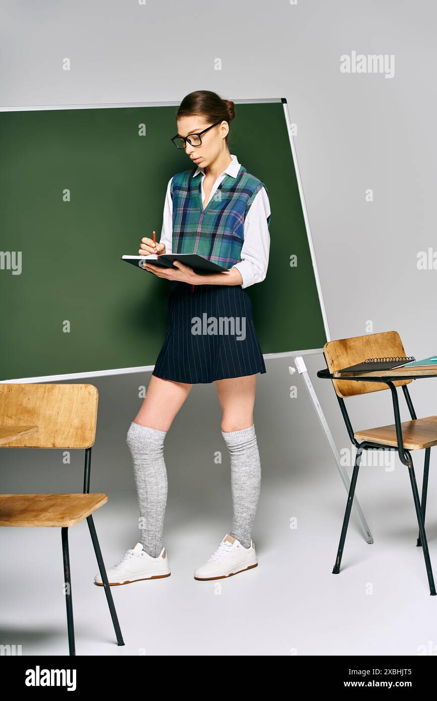 Eine Frau in Uniform steht an einer grünen Tafel. Stockfoto