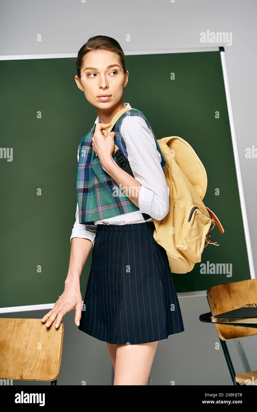 Studentin im Rock und Rucksack steht vor der Tafel. Stockfoto