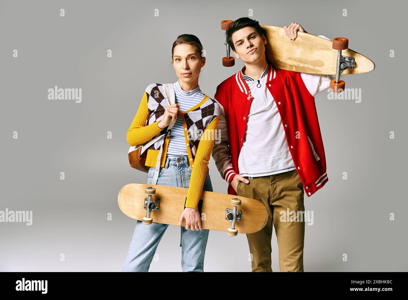 Zwei Jugendliche halten Skateboards vor grauem Hintergrund. Stockfoto