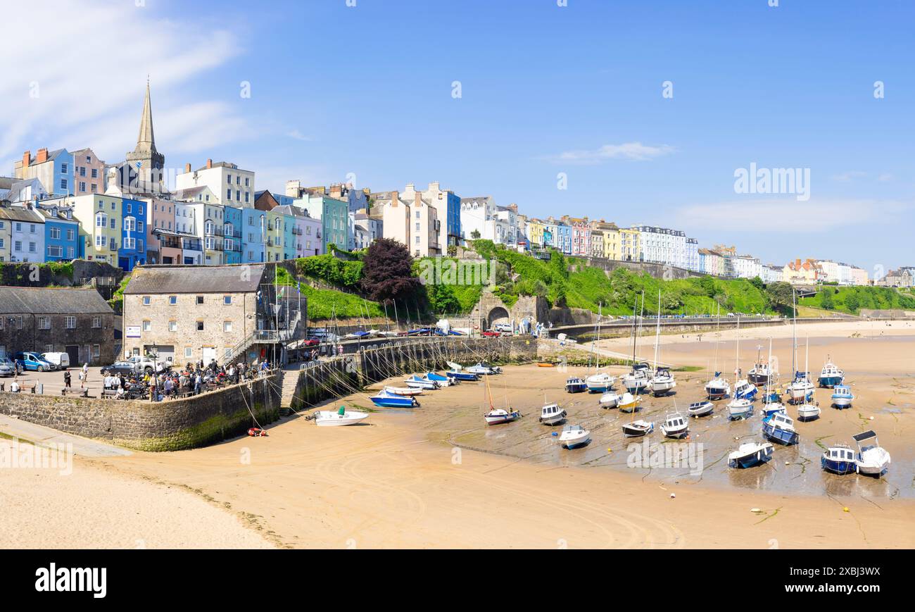 Tenby farbenfrohe Häuser oberhalb des Hafens mit kleinen Booten, die bei Ebbe im Tenby-Hafen liegen, Tenby-Carmarthan-Bucht Pembrokeshire Westwales Großbritannien GB Europa Stockfoto