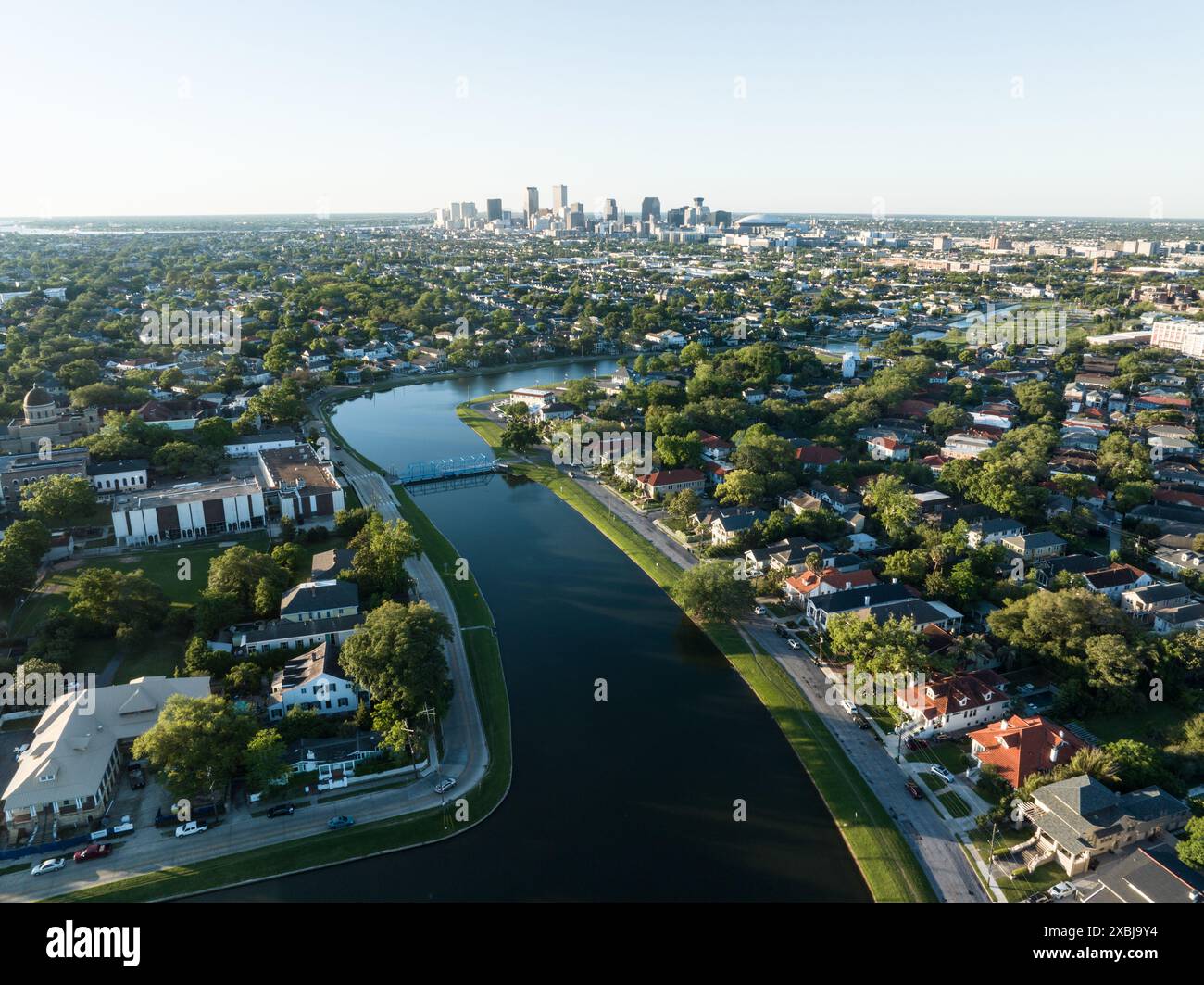 Aus der Vogelperspektive auf das historische Bayou St. John, das sich durch ein üppiges Viertel von New Orleans schlängelt, mit der Skyline der Stadt in der Ferne. Stockfoto