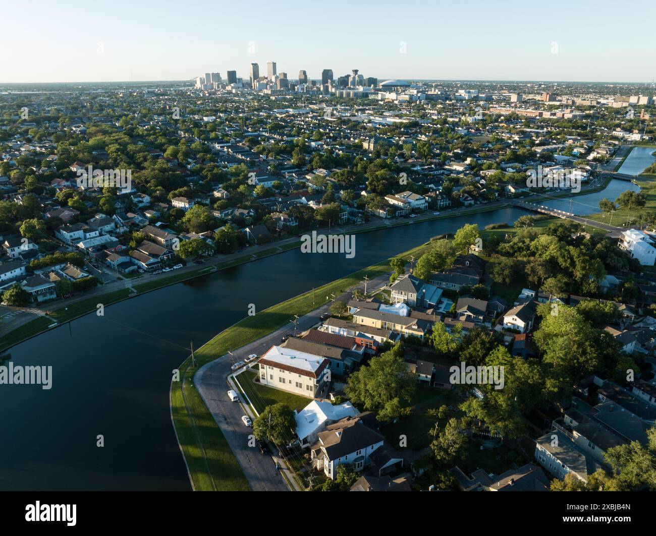 Aus der Vogelperspektive auf das historische Bayou St. John, das sich durch ein üppiges Viertel von New Orleans schlängelt, mit der Skyline der Stadt in der Ferne. Stockfoto