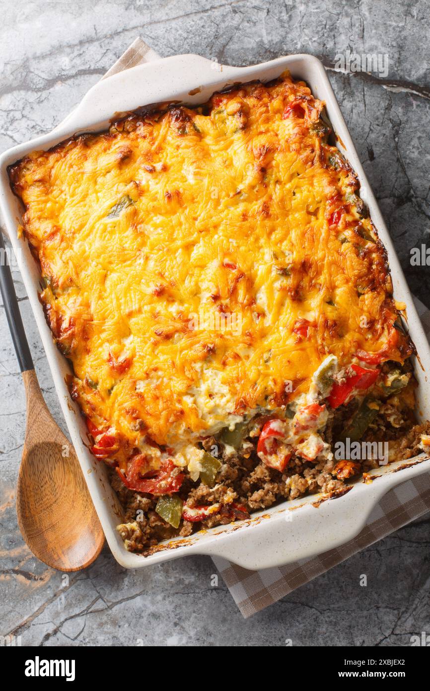 John Wayne Casserole ist ein Taco-Rinderauflauf, der in Keksteig mit Sauerrahm, Cheddar, Tomaten und Paprika aus der Nähe auf der Backform o zubereitet wird Stockfoto