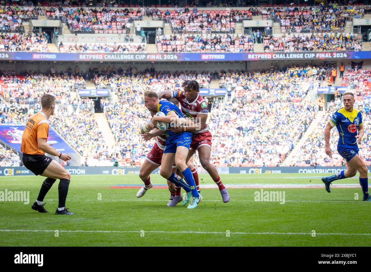 Das Finale Des Betfred Challenge Cups 2024. Junior Nsemba kämpft gegen James Harrison vor dem Schiedsrichter Chris Kendall Stockfoto