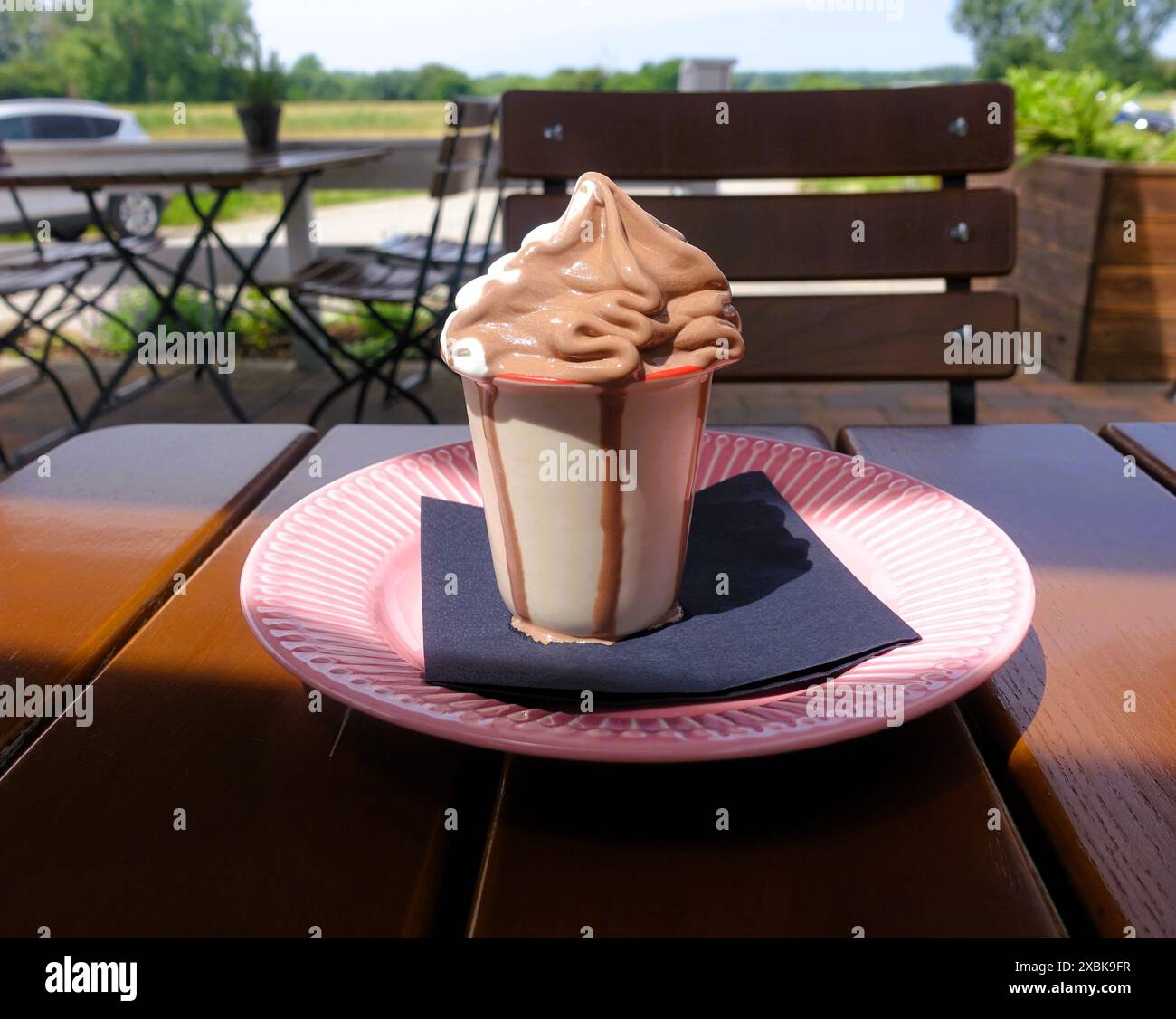 Eine Tasse Schokoladeneis auf einem rosafarbenen Teller draußen an einem sonnigen Tag Stockfoto