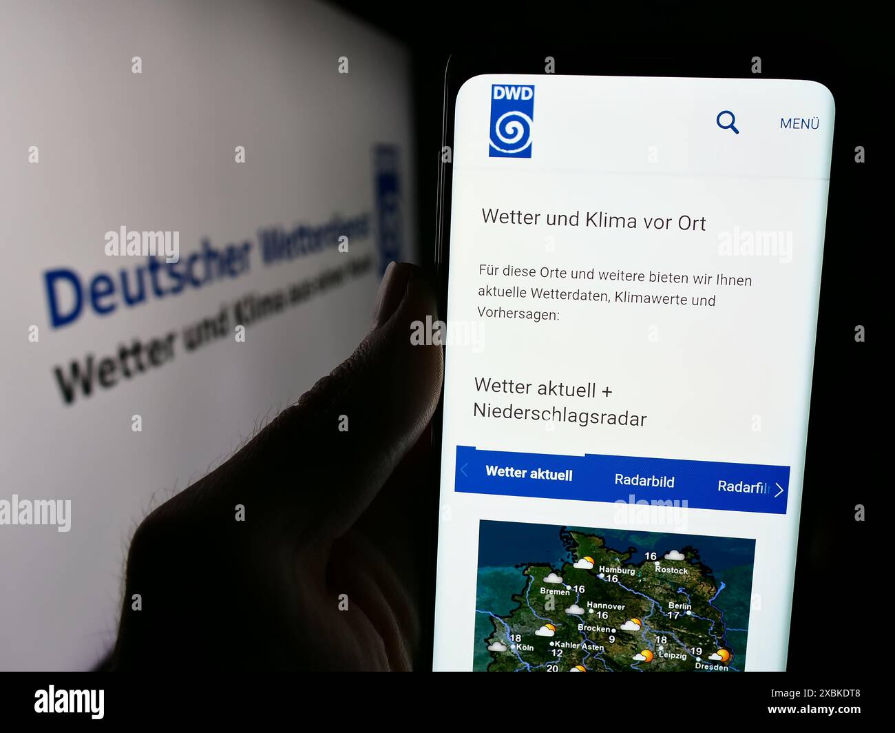 Handybesitzer mit Webseite des Deutschen Wetterdienstes (DWD) mit Logo. Konzentrieren Sie sich auf die Mitte des Telefondisplays. Stockfoto