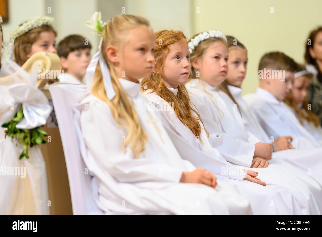 Kinder in Bänken bei ihrer ersten Kommunionmesse. Stockfoto