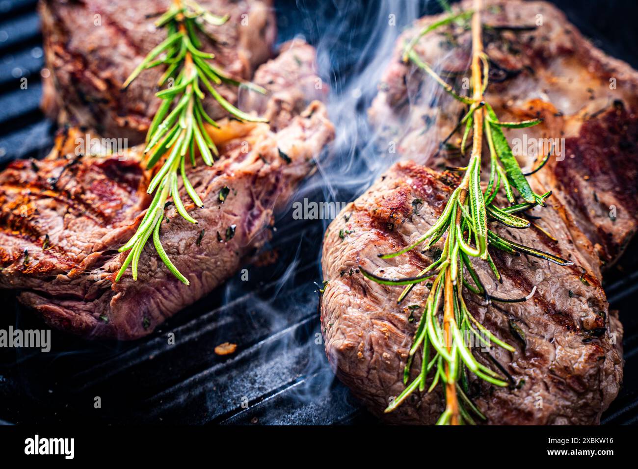 Marmoriertes Rindfleisch und Rosmarinsteaks werden gegrillt und gedämpft. Nahaufnahme. Hochwertige Fotos Stockfoto