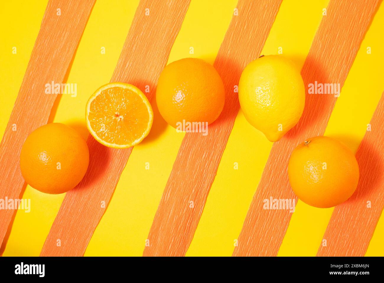 Orangen und Zitronen auf gelb-orangefarbenem Hintergrund. Kreatives Sommerkonzept. Stockfoto