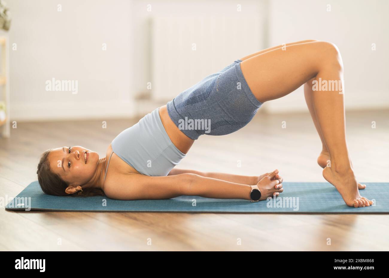 Sportliches Mädchen, das eine Brückenhaltung des Yoga in einem hellen Raum praktiziert Stockfoto