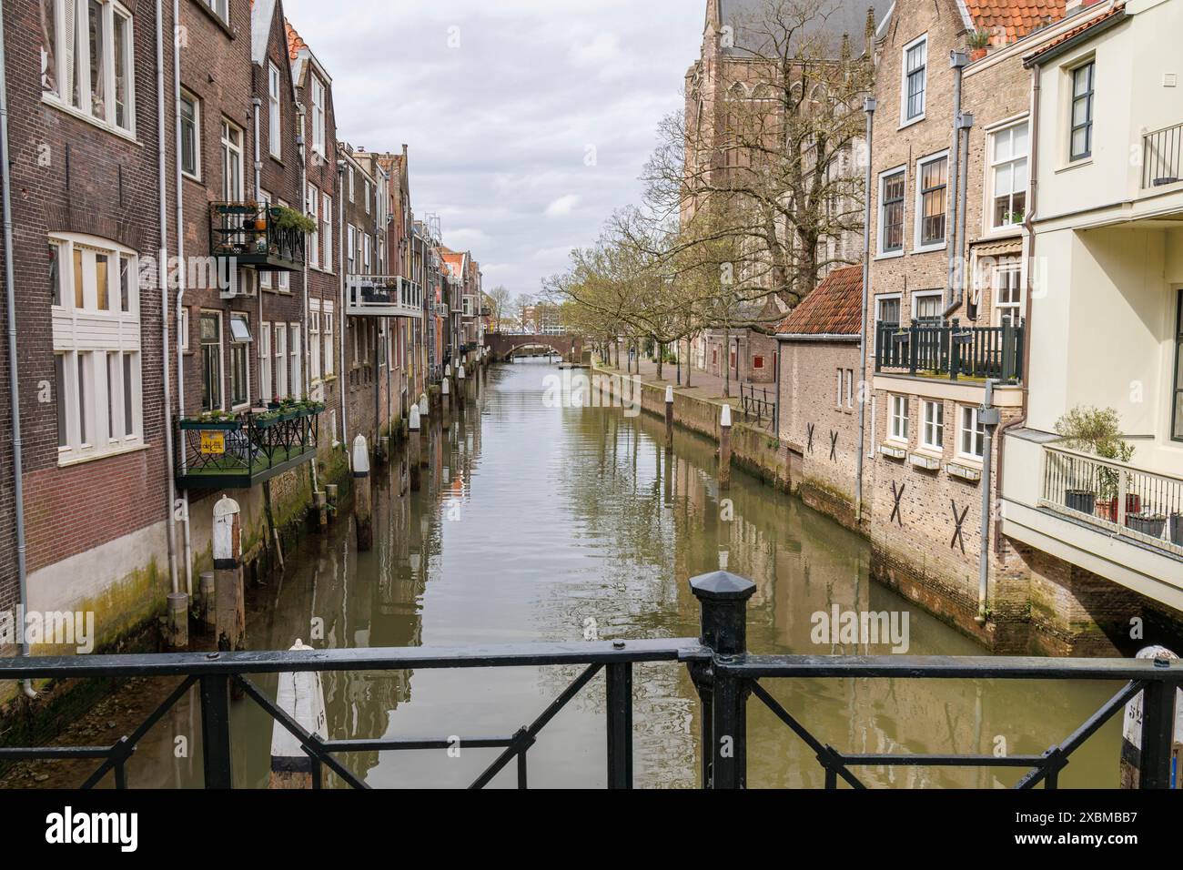 Idyllischer Kanal mit alten Gebäuden und Bäumen unter bewölktem Himmel, Dordrecht, holland, niederlande Stockfoto