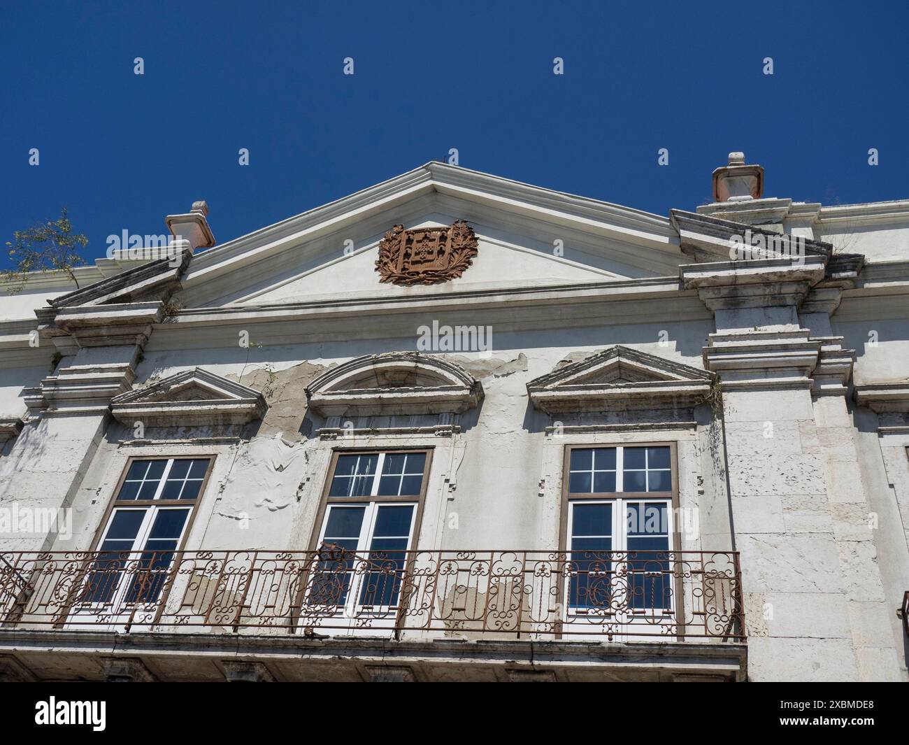 Weißes historisches Gebäude mit mehreren Fenstern, leichtem Riss in der Fassade und klarem blauem Himmel, Lissabon, portugal Stockfoto