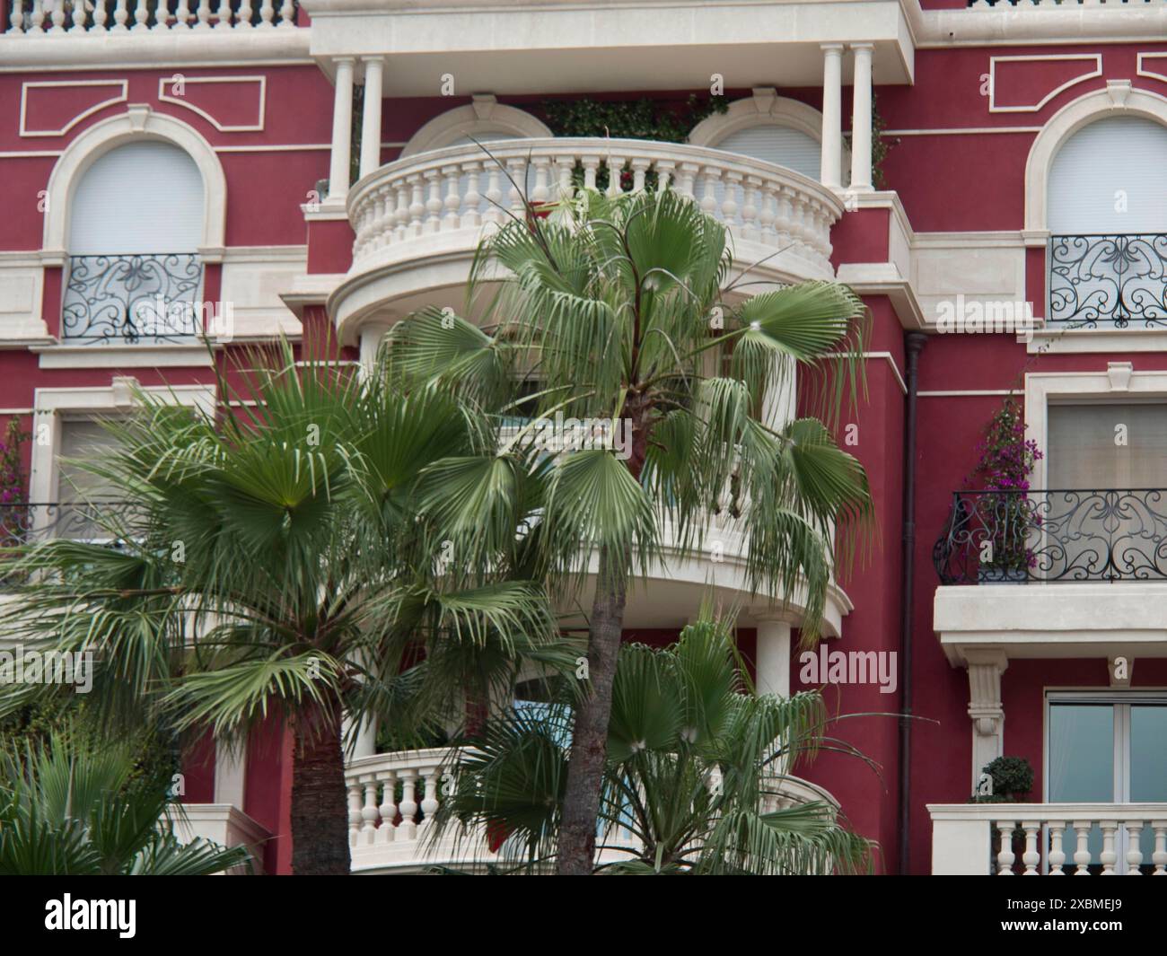 Rote Fassade mit mehreren eleganten Balkonen und üppigen Pflanzen, monte carlo, monaco, frankreich Stockfoto
