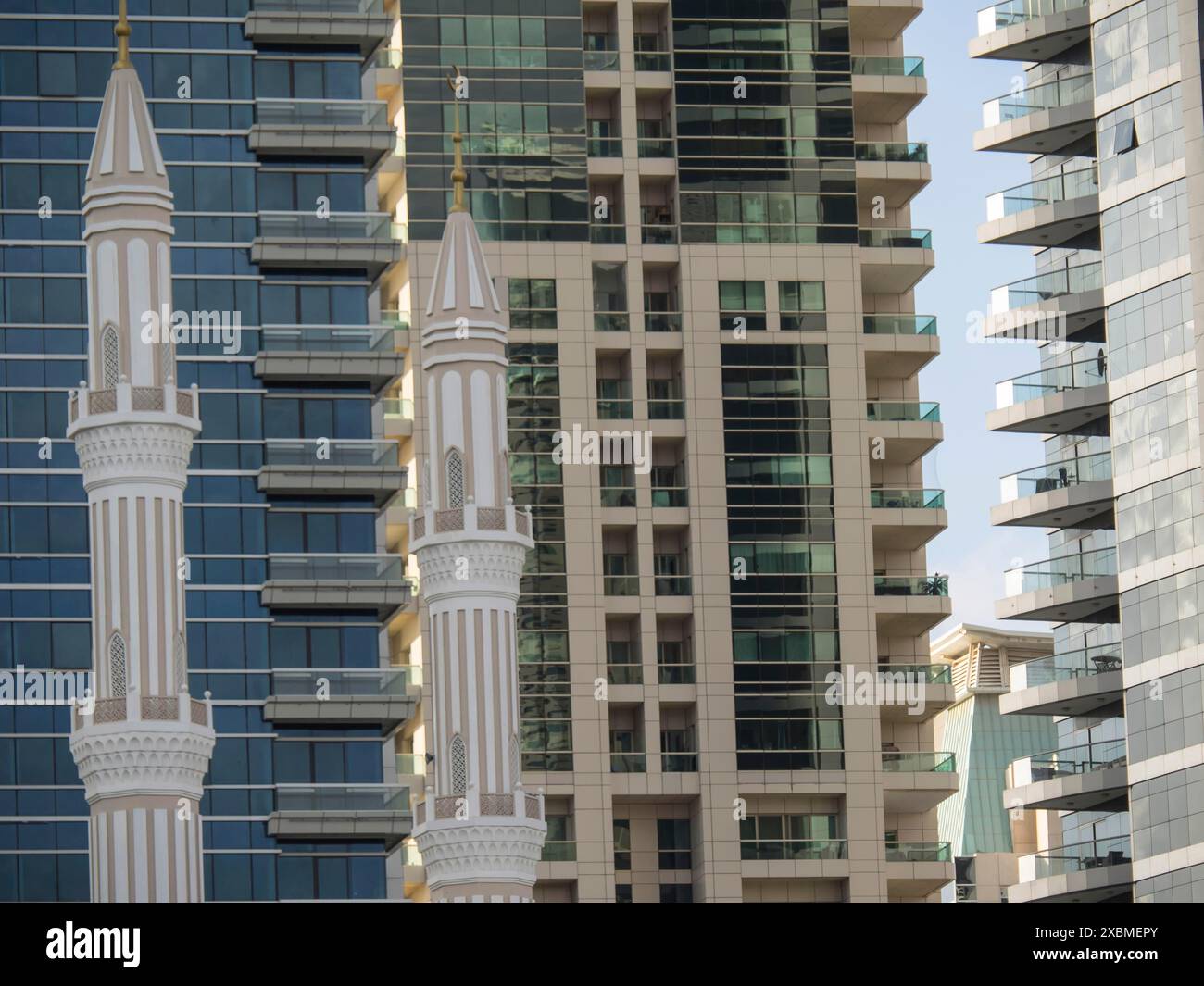 Ein moderner Wolkenkratzer und ein traditionelles Minarett nebeneinander, das architektonische Vielfalt repräsentiert, abu dhabi, vereinigte arabische emirate Stockfoto