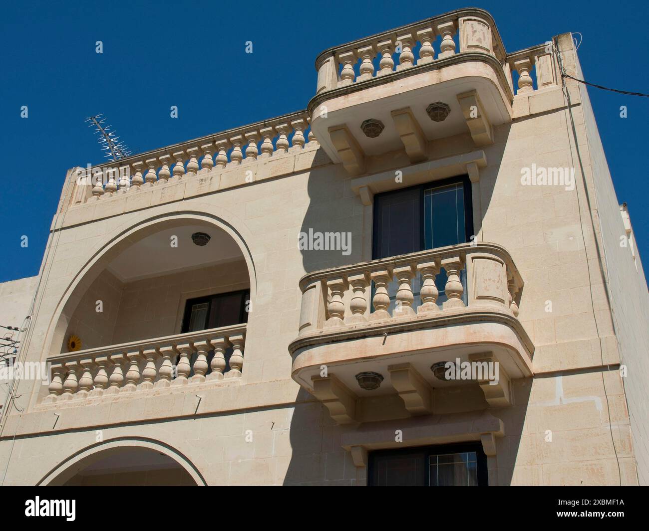 Mehrstöckiges Gebäude mit Balkonen und Fenstern unter klarem blauem Himmel, Gozo, Mittelmeer, Malta Stockfoto