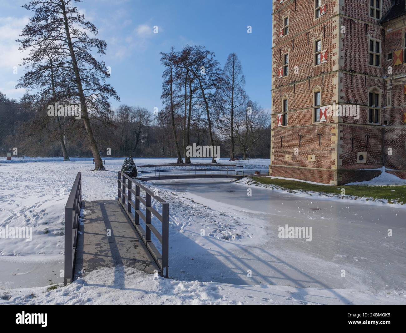 Historisches Schloss und gefrorener Fluss im Winter mit schneebedecktem Gelände und Brücke, sonnig und klar, Raesfeld, münsterland, deutschland Stockfoto