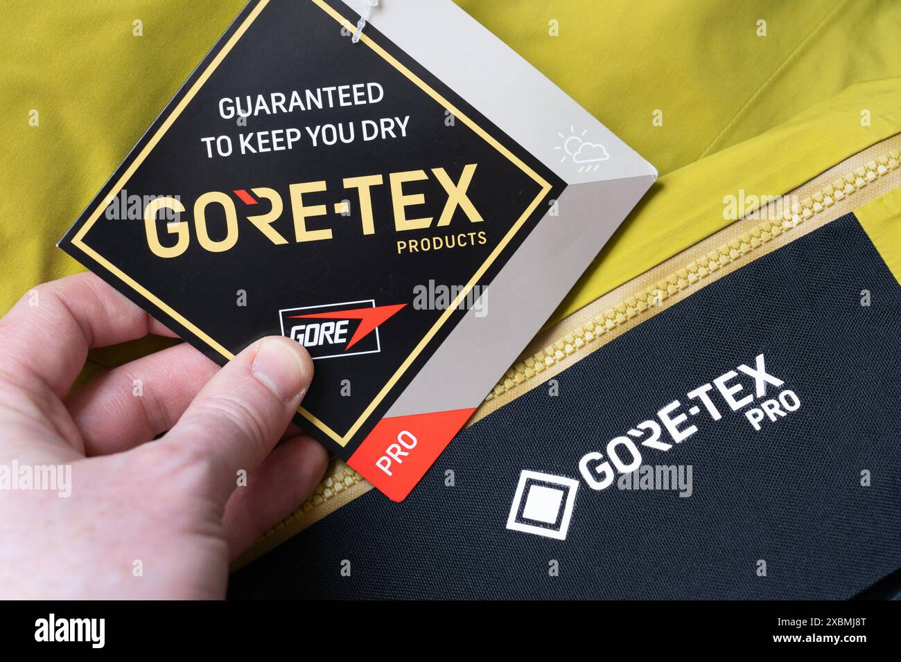 Die Hand des Mannes hält ein Etikett auf einer Wanderhose, die Gore Tex Material, Großbritannien, anwarnt. Gore Tex wird aus expandiertem Polytetrafluorethylen (PTFE) hergestellt Stockfoto