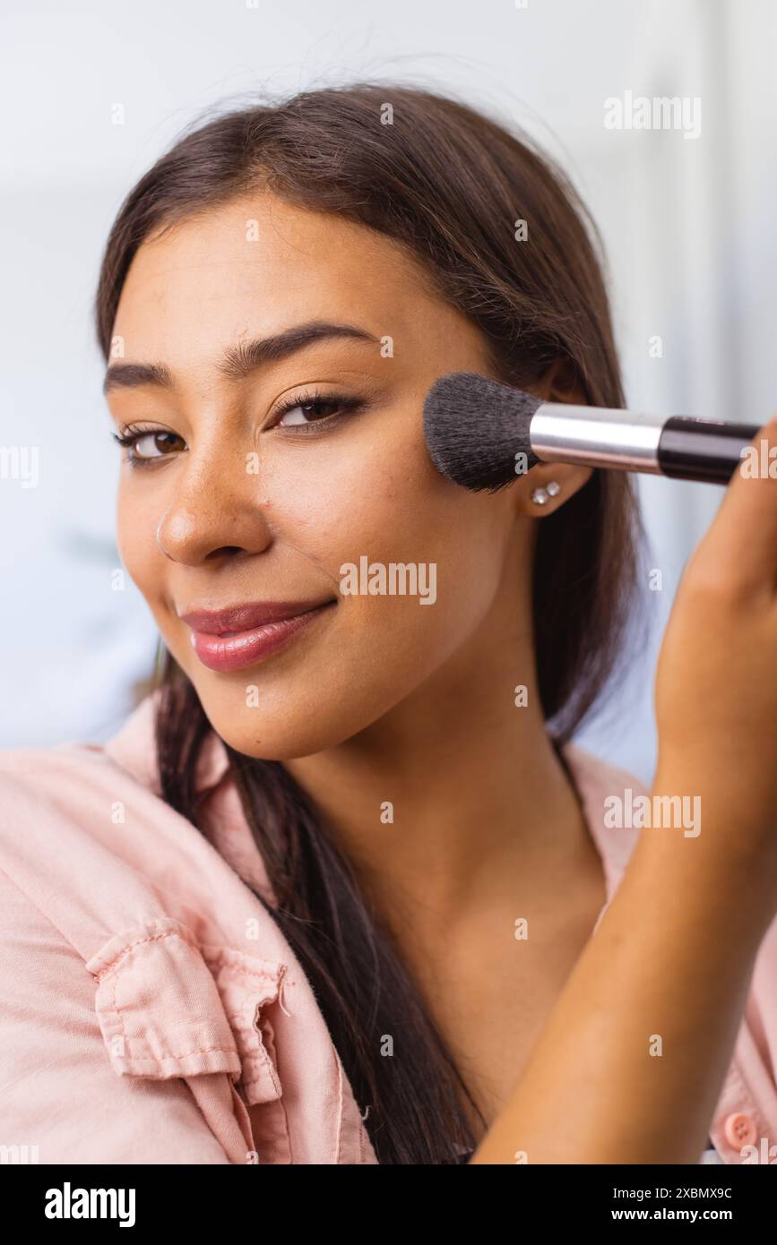 Glückliche Frau, die mit Pinsel Make-up aufträgt, selbstbewusst lächelt Stockfoto