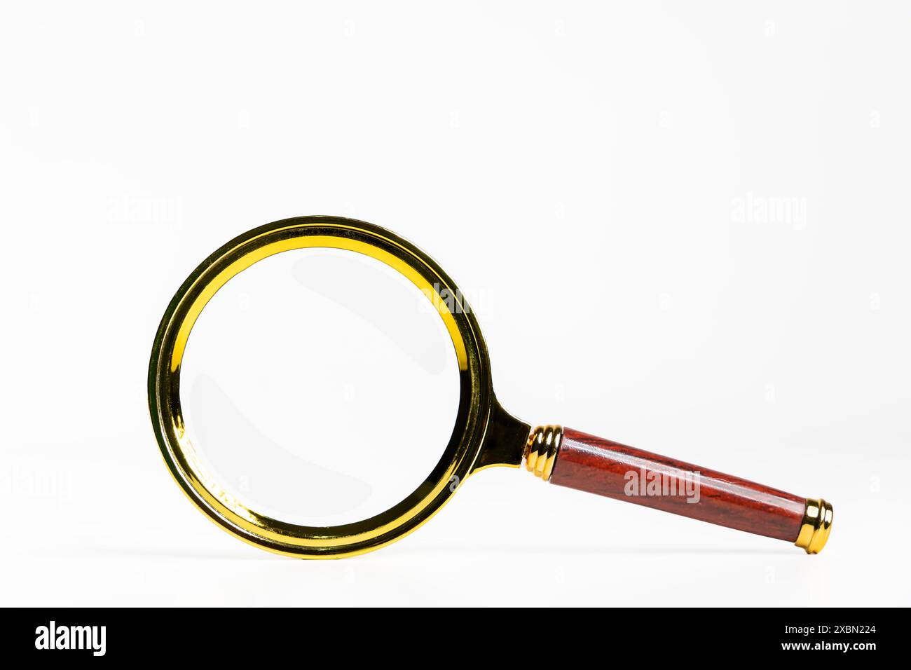 Eine Lupe mit Holzgriff ist auf weißem Hintergrund abgebildet. Konzept der Neugier und Erkundung, wie es oft mit der Lupe üblich ist Stockfoto