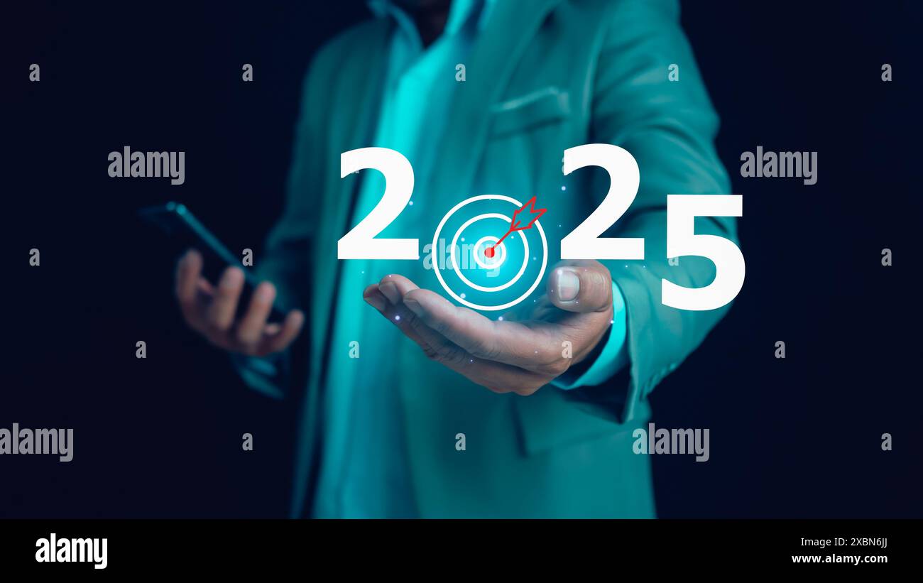 Geschäftsmann hält Text 2025 mit Pfeilziel, Umsetzung des Geschäftszielplans, Festlegung von Zielen für 2025, Entwicklung zum Erreichen von Zielen und Erfolg. Stockfoto