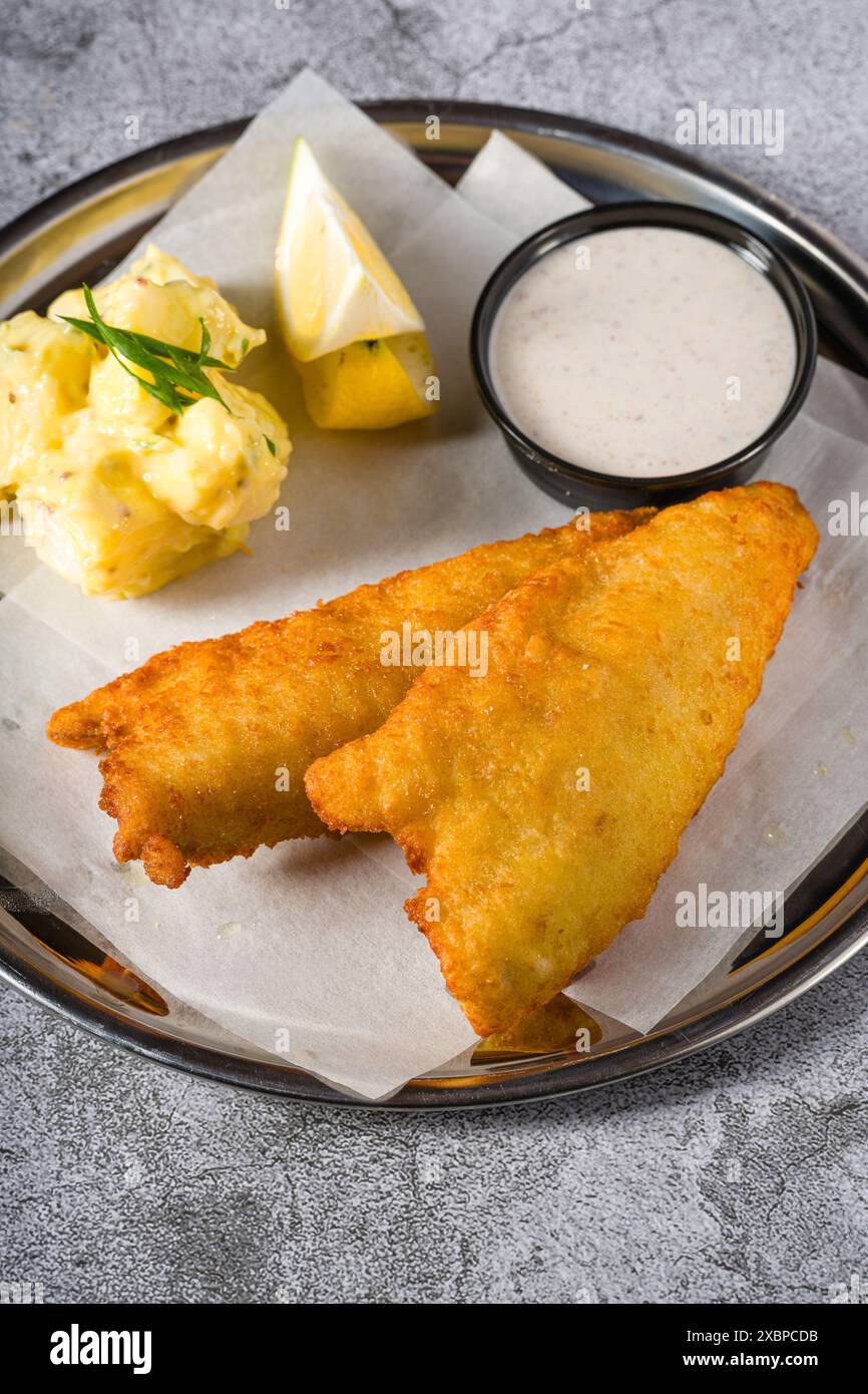 Frittiertes, beschichtetes Fischfilet mit Kartoffelsalat auf Steintisch Stockfoto