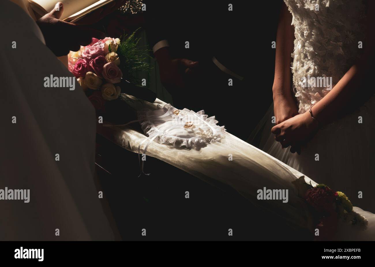 Hochzeitszeremonie in einer Kirche mit einem Priester, der eine Bibel hält, und einem frisch verheirateten Paar, das Ringe austauscht Stockfoto