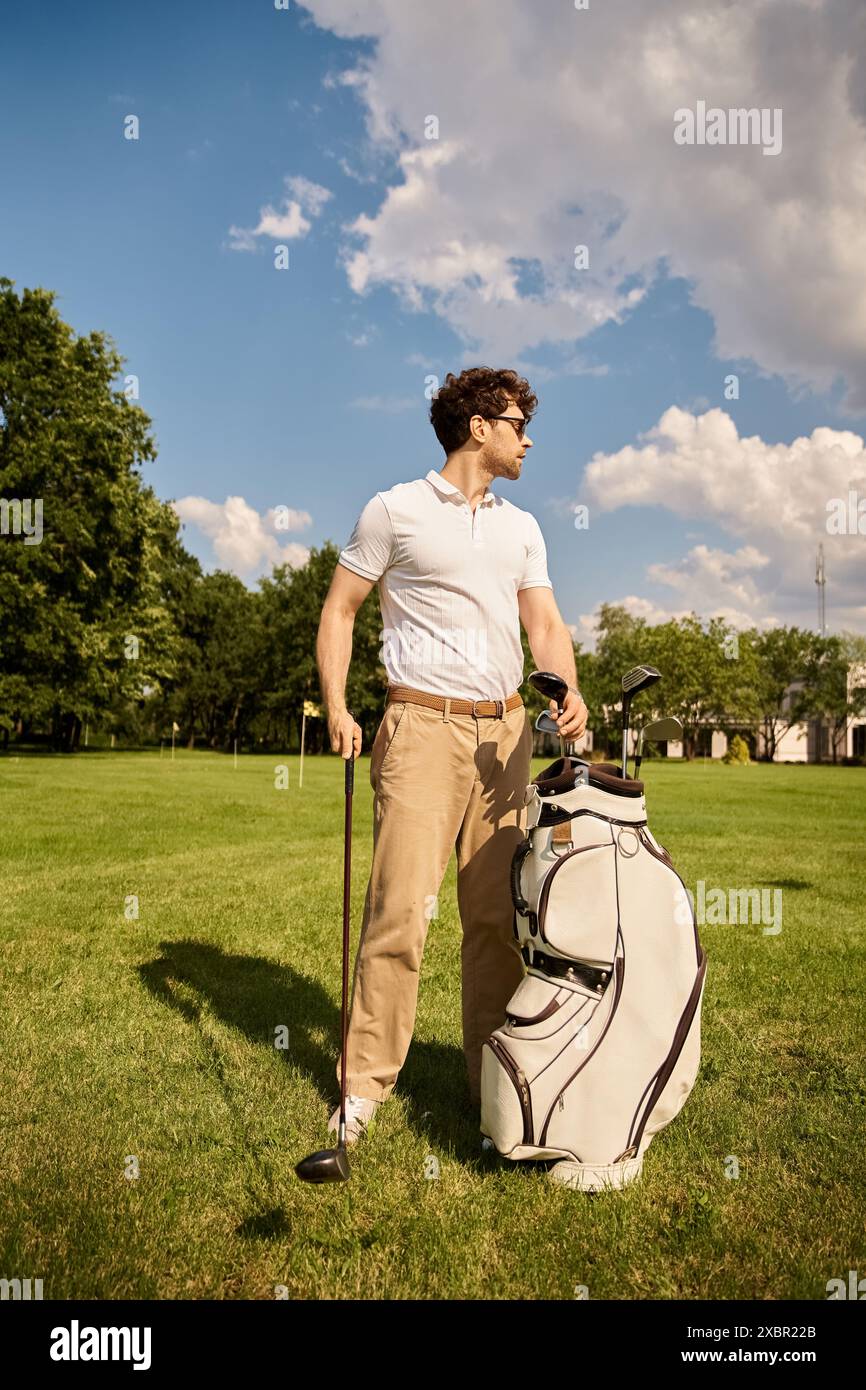 Ein Mann steht auf einem Grasfeld mit einer Golftasche und verkörpert einen gehobenen Lebensstil in einem eleganten Golfclub. Stockfoto