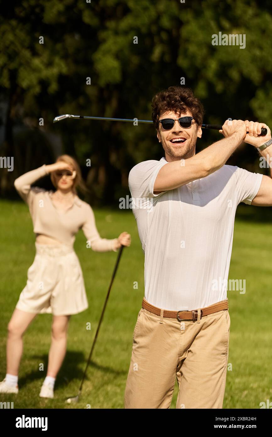 Ein stilvoller Mann und eine stilvolle Frau spielen Golf in einem Park und genießen eine gemütliche Runde an einem sonnigen Tag. Stockfoto