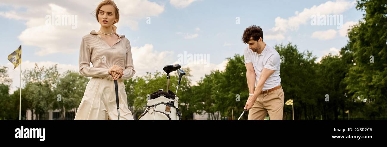 Ein junges Paar in stilvoller Kleidung spielt eine Runde Golf in einem Park und genießt einen entspannten Tag auf dem Grün. Stockfoto