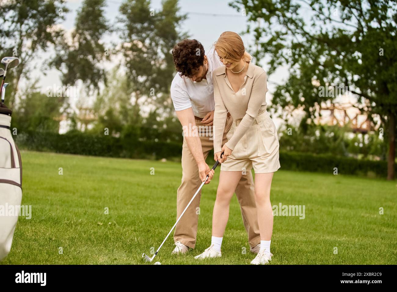 Ein junges Paar in eleganter Kleidung genießt eine Partie Golf auf einem üppigen grünen Feld in einem erstklassigen Golfclub. Stockfoto