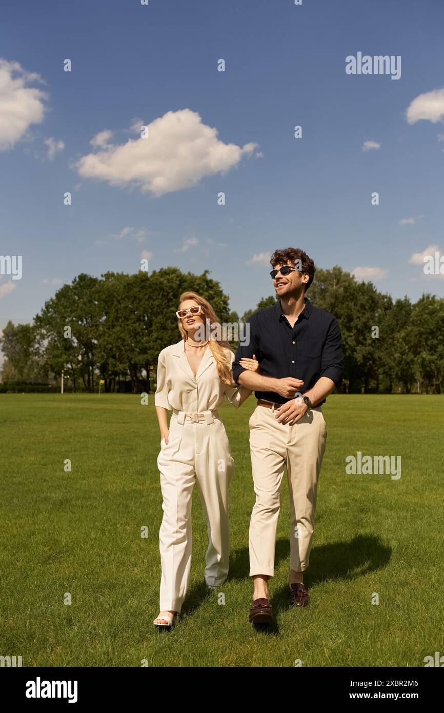 Ein elegantes Paar spaziert gemütlich zusammen durch ein üppiges grünes Feld, das alte Geld Raffinesse und Luxus ausstrahlt. Stockfoto