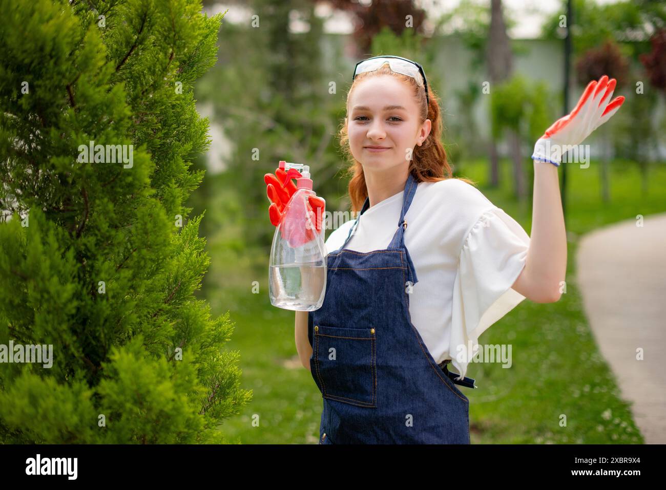 Junge Frau, die Baum sprüht, zeigt, die Hand hebt, in die Kamera schaut. Stockfoto