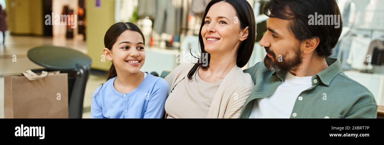 Eine glückliche Familie sitzt im Einkaufszentrum, umgeben von Einkaufstaschen, nach einem erlebnisreichen gemeinsamen Einkaufstag. Stockfoto