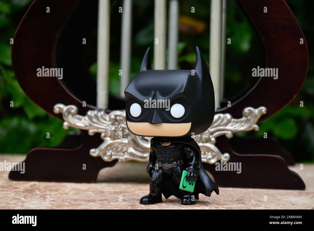 Funko Pop Actionfigur des DC-Superhelden Batman Bruce Wayne hält Riddlers Nachrichtenkarte. Miniatur-Pavillon, Palast mit Säulen. Stockfoto